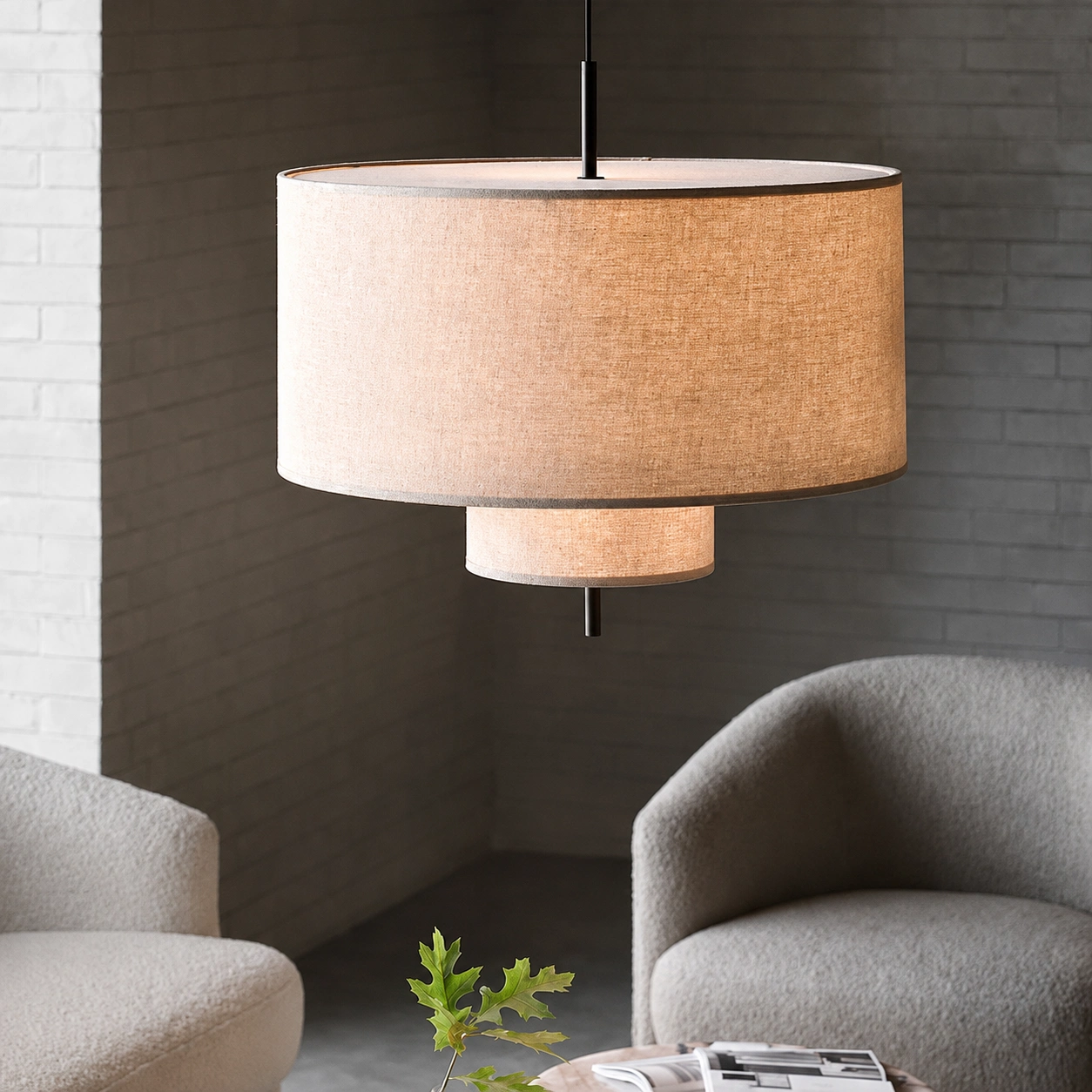 Close up of double layer linen drum pendant light with black metal frame and warm glow